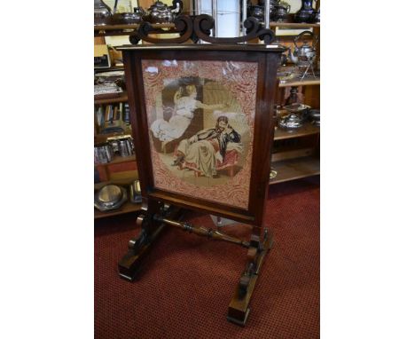 A Victorian rosewood firescreen with scrolled surmount over a tapestry depiction of Charles I and Angel, all raised on a scro