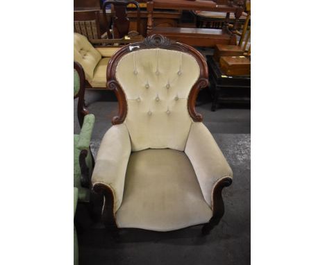 A Victorian mahogany easychair, having a deep button spoon back surmounted with carved cresting over the scrolled out arms wi
