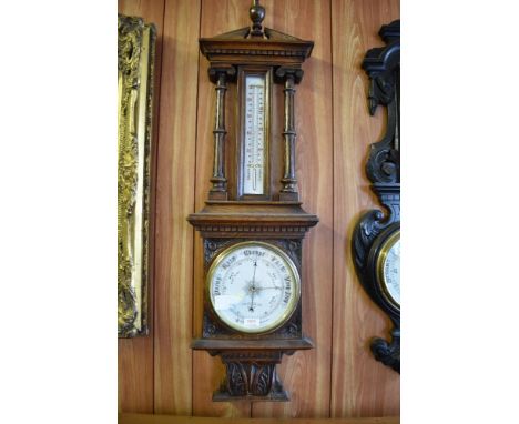 A Victorian carved oak barometer, having an architectural pediment with central urn form finial over a dentil moulded frieze 