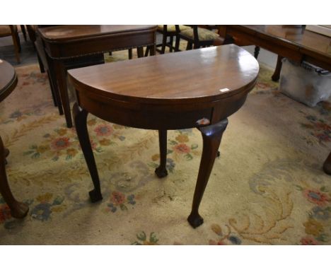 A 1920s demilune foldover card table raised on cabriole type supports terminating in claw and ball feet  79 CM X 91CM.
