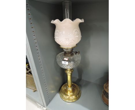 A vintage oil lamp with brass base and pink pressed glass shade