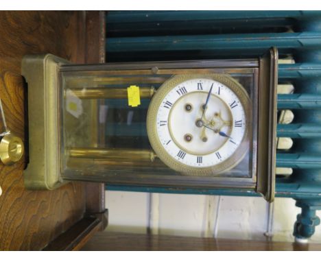 A late 19th century brass mantel clock, with glazed sides, and enamel dial on columns, the dial with exposed jewelled Brocot 