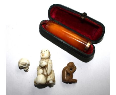 Two ivory netsuke in the form of a skull and a figure, another monkey netsuke and an amber cheroot holder, cased (4)