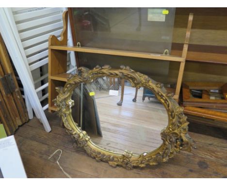 An Italian style gilt gesso wall mirror, the oval plate in a floral scroll frame 66cm x 49cm and a pine wall shelf (2)