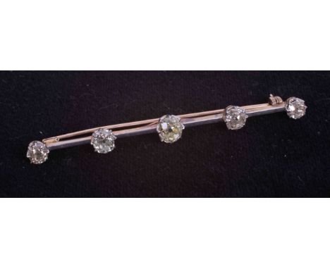 A yellow &amp; white gold (not hallmarked or tested) bar brooch set with five old cut diamonds some round and some slightly c
