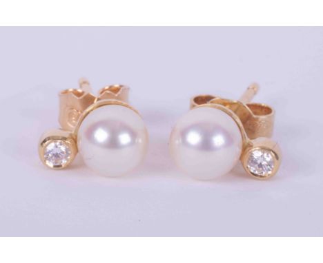 A pair of 18ct yellow gold studs set with a 5.5mm cultured pearl and a small round brilliant cut diamond, with post and butte