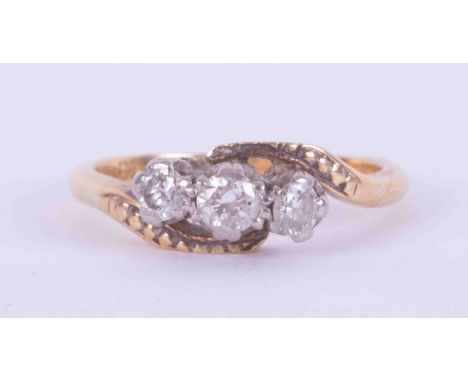 An 18ct yellow &amp; white gold three stone twist ring set with approx. 0.25 carats total weight of round brilliant cut diamo