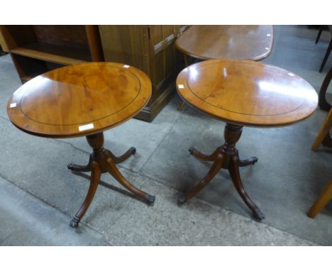 A pair of yew wood circular tripod wine tables 