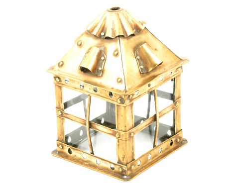 An Arts and Crafts brass hall lantern, the square body with pitched roof with vents and fluted top, and convex protective gri