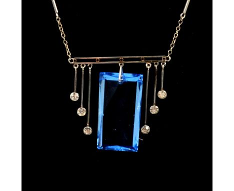 A blue paste crystal pendant and chain in the Art Deco style, the scissor cut stone 25x12mm suspended from a horizontal bar w