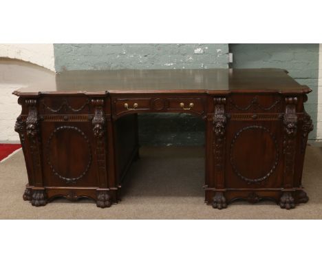 A large carved mahogany partners desk decorated with lion masks, festoons and raised on lion paw feet with brass mounts. Afte