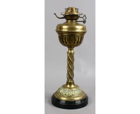 A brass based oil lamp with twist decoration raised on a glazed pottery plinth.