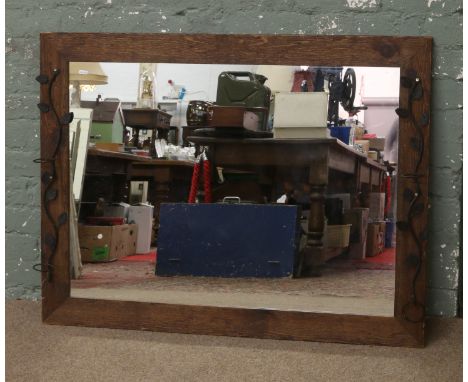 An oak rectangular framed mirror with floral effect iron work decoration.