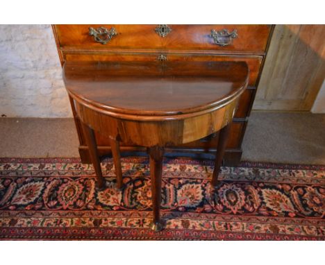 A George III Mahogany Demi Lune Card Table, the hinged top above a plain frieze raised upon turned tapering legs with pad fee