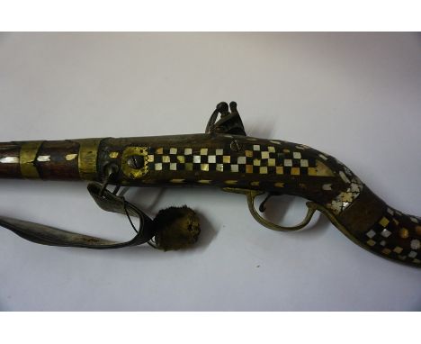 An Indian Flintlock Gun, circa early 19th century, Having a metal ramrod, The walnut stock and butt decorated with mother of 