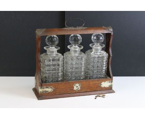 Early 20th century oak tantalus with three square cut decanters and plated mounts, approx. H 33cm