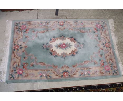 Green Chinese rug with pastel coloured border and centre floral plaque, measures 186cm x 120cm