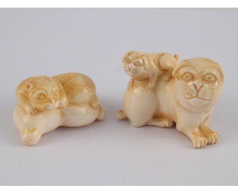 Two netsuke , circa 1920. One a pug dog with pup, signed, and a dog lying on a cushion, both signed.
