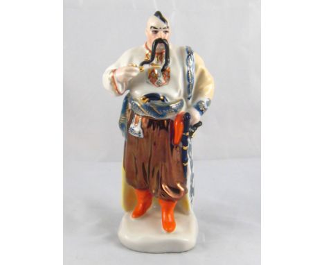 A Russian ceramic figure of a man in traditional dress. Blue factory mark to base. Ht. 22cm. 