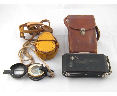 A marching compass with prismatic sight and lanyard in leather case with shoulder strap, together with a Kodak folding camera