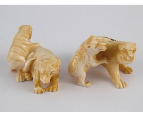 Two ivory netsuke, circa 1920, one of a tiger and cub, the other a bear and cub, both signed. 