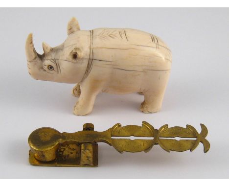 An ivory rhinoceros, one ear damaged, length 8cm., together with a pair of brass sovereign scales stamped "Sovereign Warrante