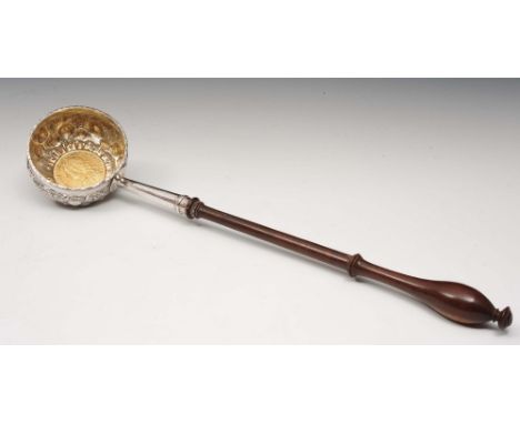 A Georgian white metal toddy ladle with embossed fruit decoration and coin inset, with turned walnut handle