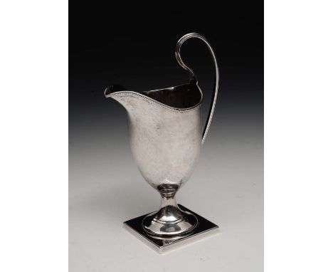 A Georgian style helmet shaped cream jug on square cut pedestal foot with beaded and shaped loop handle, Birmingham 1906, 98 