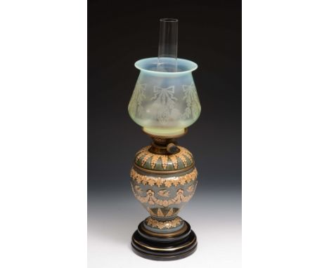 A Doulton stoneware oil lamp of green ground decorated with swallows, on a circular base, with etched opaque shade, 48cm high