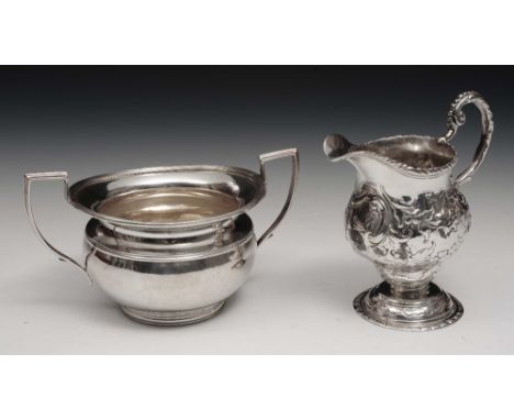 A Georgian silver helmet shaped cream jug of baluster form on pedestal foot with gadroon borders and embossed decoration, mar