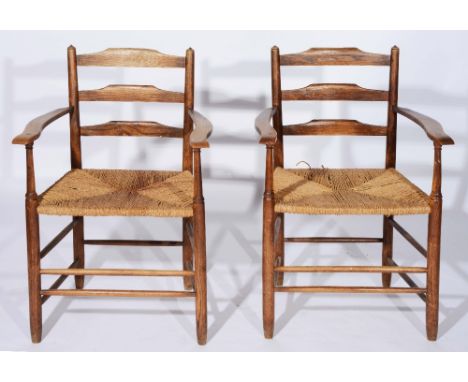 A set of eleven Cotswold School Clissett style ladder back dining chairs each with rush seat ,in the manner of Gimson, circa 