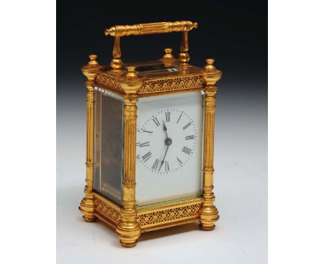 A brass and gilt carriage clock with enamel dial, swing handle, relief borders and turned pillars