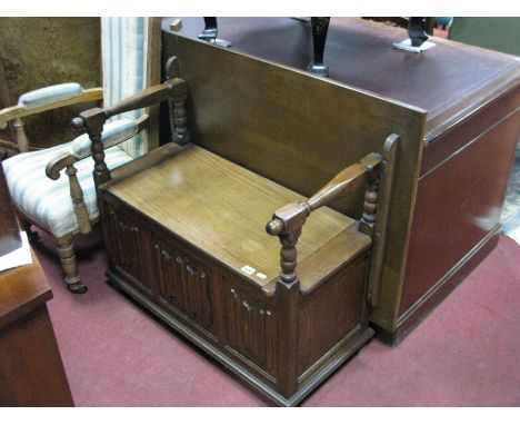An Oak Monks Bench, with bobbin supports and linenfold fascia.