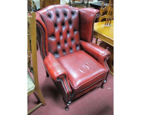 A XX Century Red Leather Armchair, with button back and stud decoration, on small cabriole legs.