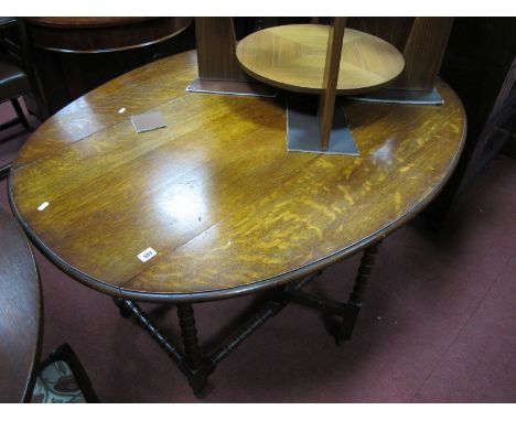 A 1920's Oak Drop Leaf Table, with an oval top, moulded edge, on bobbin turned legs.