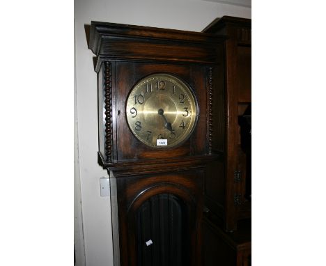 Oak longcase clock circa 1930, the circular brass dial with Arabic numerals and two train weight driven movement