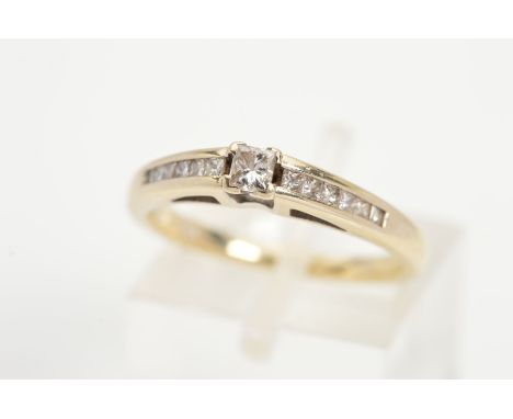 AN 18CT GOLD DIAMOND RING, designed as a central princess cut diamond with channel set princess cut diamond shoulders, estima