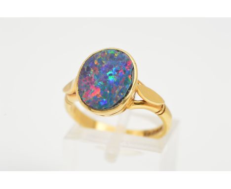 AN 18CT GOLD OPAL RING, designed as an oval opal doublet in a collet mount, to the plain polish detail shoulders, with an 18c