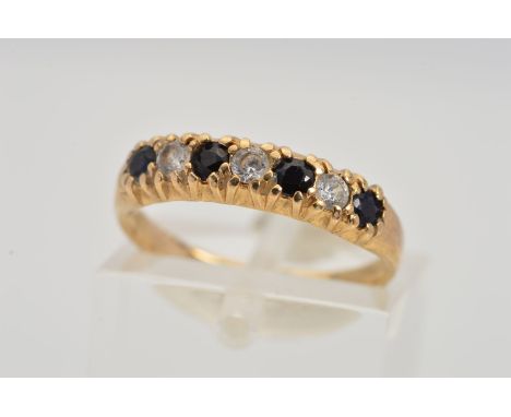 A 9CT GOLD SEVEN STONE RING, designed as a row of four circular sapphires interspaced by circular colourless gems assessed as