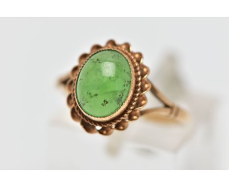 A 9CT GOLD CHRYSOPRASE SINGLE STONE RING, the oval chrysoprase cabochon collet set with rope twist surround, to the bifurcate