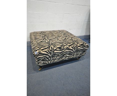 A SQUARE ZEBRA PRINT UPHOLSTERED FOOSTOOL, on turned legs and brass casters, 104cm squared x height 43cm, along with a black 