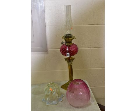 A LATE VICTORIAN OIL LAMP, the acid etched cranberry glass shade with broken section, cranberry reservoir decorated with prun