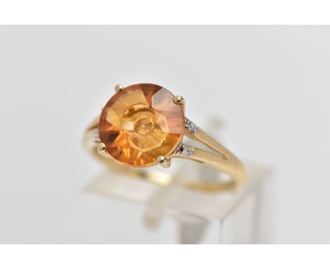 A 9CT GOLD GEM SET RING, four claw set, fancy circular cut orange stone assessed as citrine, bifurcated shoulders each set wi