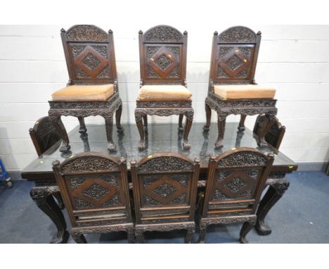 A 20TH CENTURY THAI ORIENTAL HEAVILY CARVED STAINED TEAK DINING TABLE, the recessed top with a repeating pattern, mythical ma