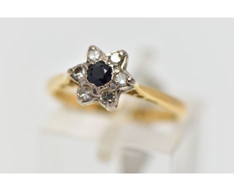 A YELLOW AND WHITE METAL CLUSTER RING, a circular cut sapphire and six single cut diamonds prong set in white metal as a flor