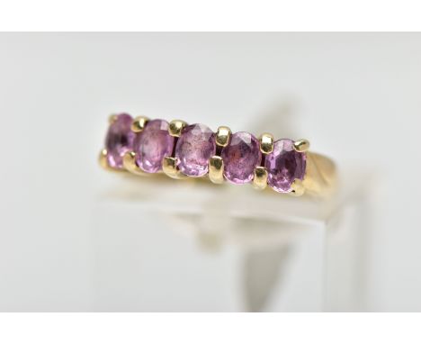 A 9CT GOLD FIVE STONE RING, designed with a row of four claw set, oval cut pink stones assessed as sapphires, polished yellow