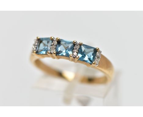 A 9CT GOLD TOPAZ AND DIAMOND DRESS RING, the cushion cut blue topaz with single cut diamond duo spacers, to the tapered shoul