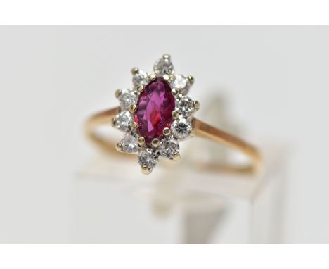 A 9CT YELLOW AND WHITE GOLD RUBY AND DIAMOND CLUSTER RING, set with a marquise shape ruby, within a round brilliant cut diamo