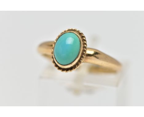 A 9CT GOLD TURQUOISE RING, designed with an oval turquoise cabochon, collet set with a fine rope twist surround, polished yel