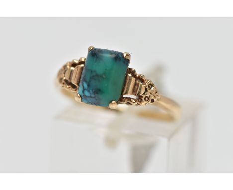 A YELLOW METAL TURQUOISE RING, rectangular blue/green turquoise cabochon, four claw set in a raised mount, scroll detailed sh